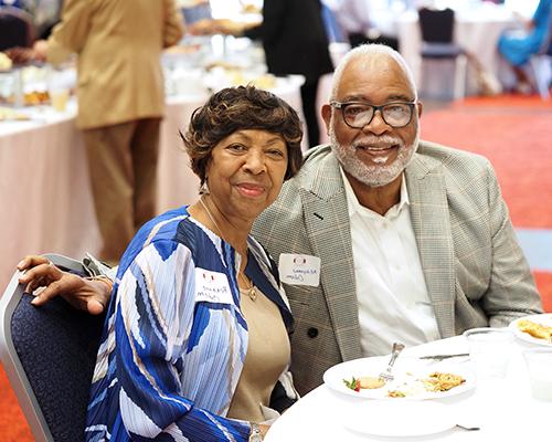 Two alumni sitting at a table in the MacQueen Center at the 1974 Society Reception.