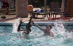 Two male students playing water basketball in Campus Rec outdoor pool.