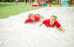 Camp counselors sliding on slip and slide.